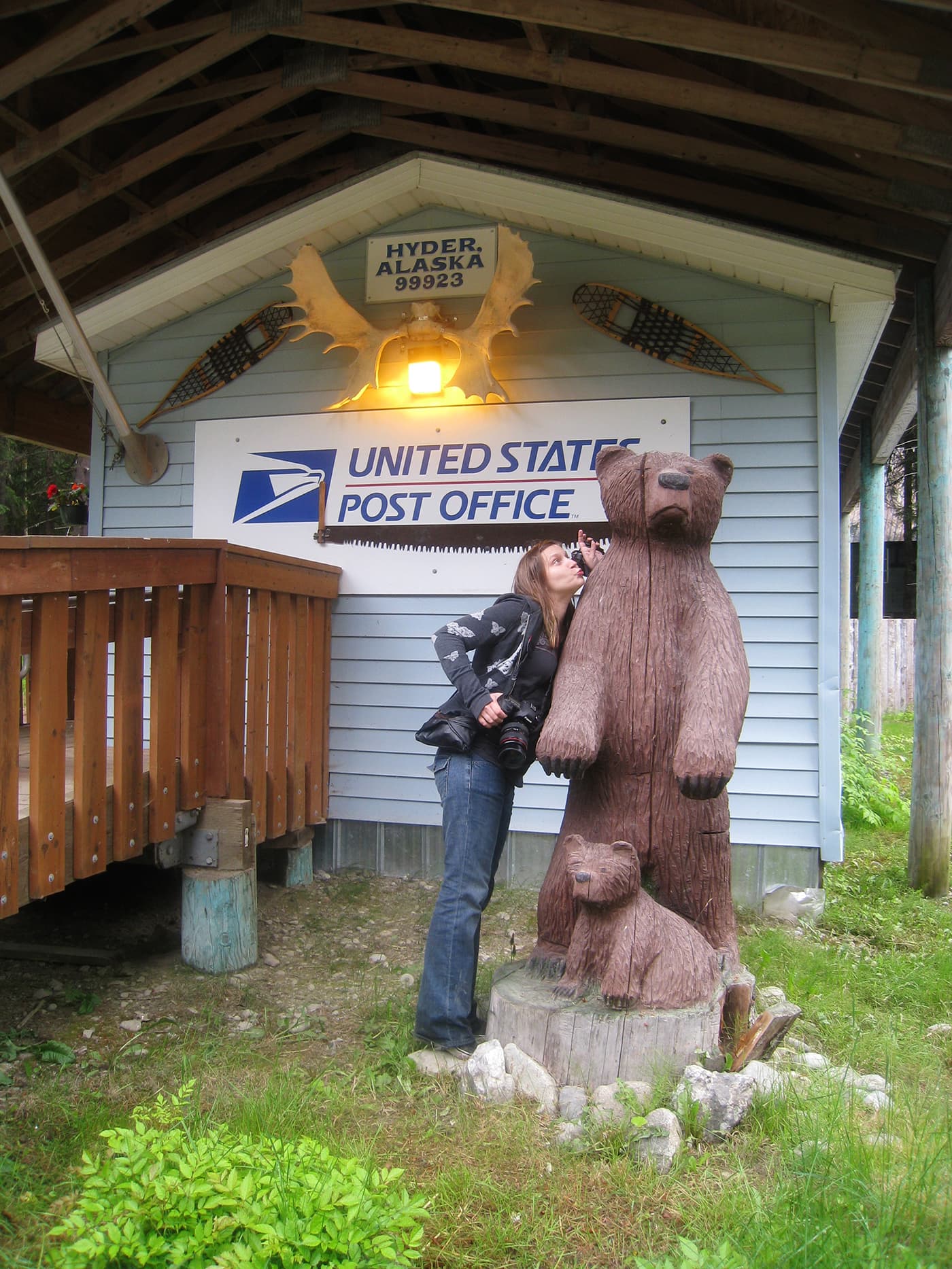 Val kisses the wooden carved bear and cub at the Hyder, Alaska Post Office.