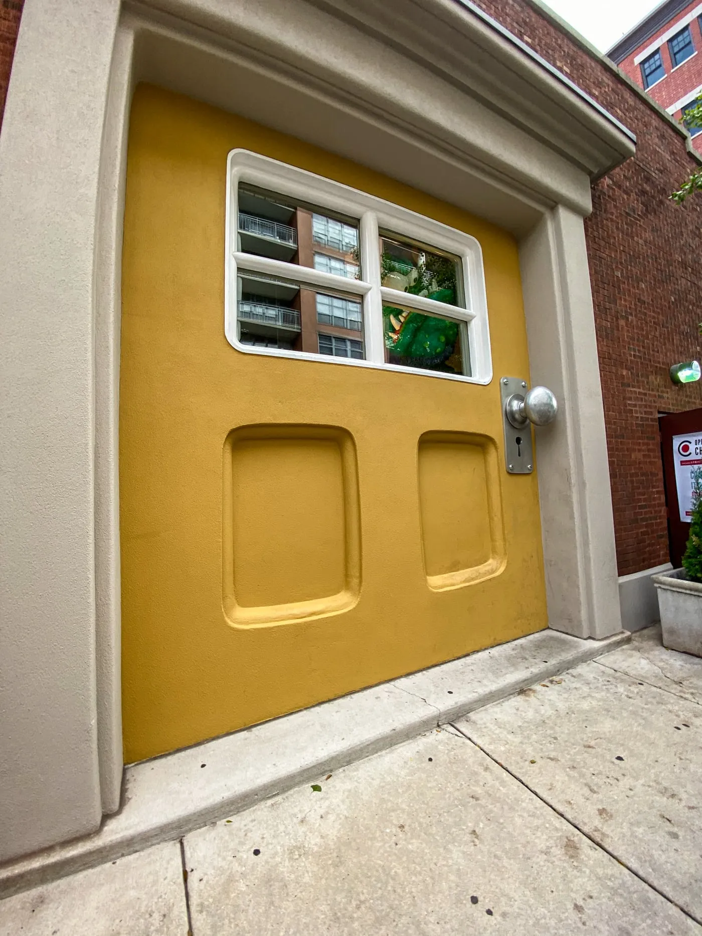 Big Monster Door at Big Monster Toys in Chicago, Illinois | A giant yellow door with a monster peeking out the window in the West Loop