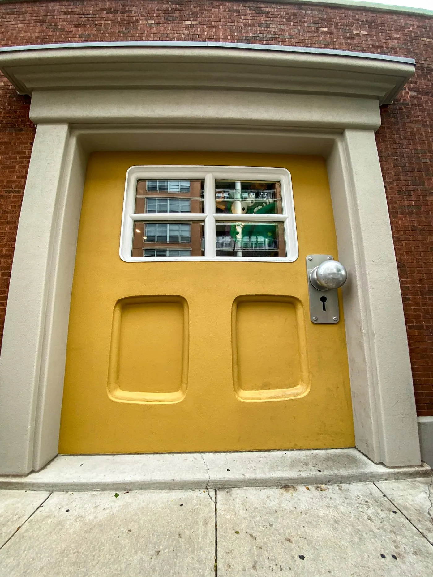 Big Monster Door at Big Monster Toys in Chicago, Illinois | A giant yellow door with a monster peeking out the window in the West Loop