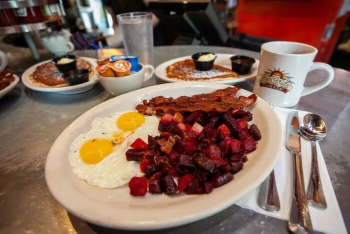 Classic diner breakfast of blueberry pancakes, red hash, bacon, and fried eggs. Road Trip Breakfast Ideas.